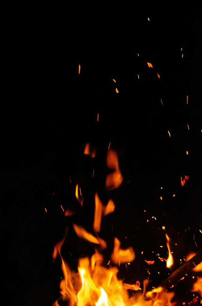 Close-up of bright flames and sparks in the dark night creating a warm ambiance.